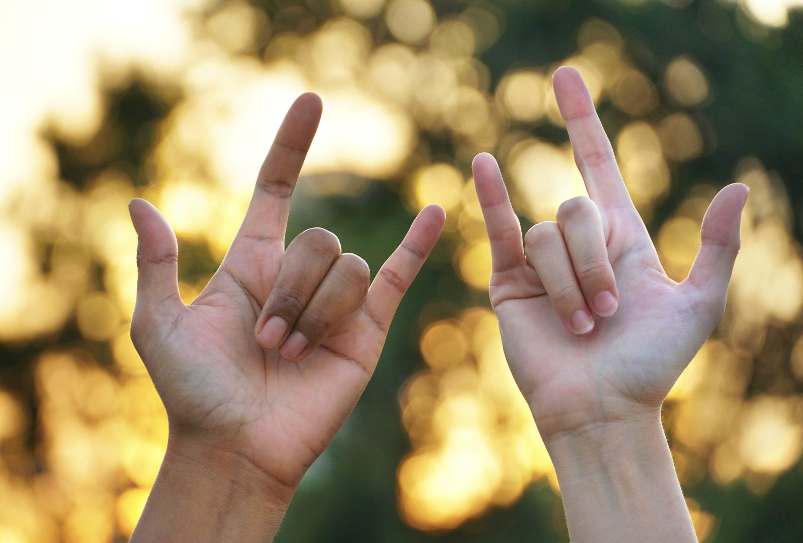 Two people holding their wrists up and doing a sign language gesture