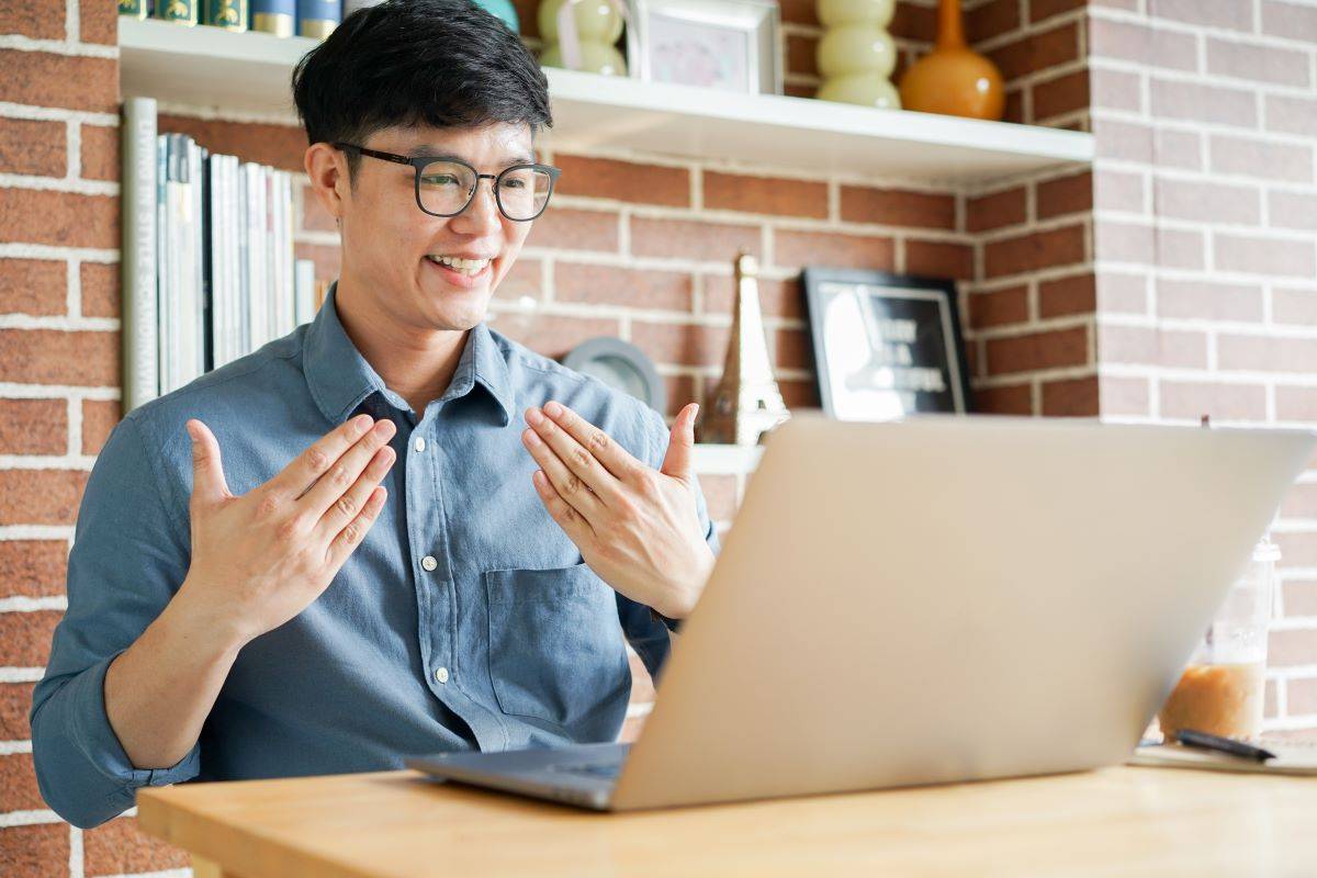A person doing a hand gesture that signifies that they are speaking to someone over the laptop screen for asl interpreter services